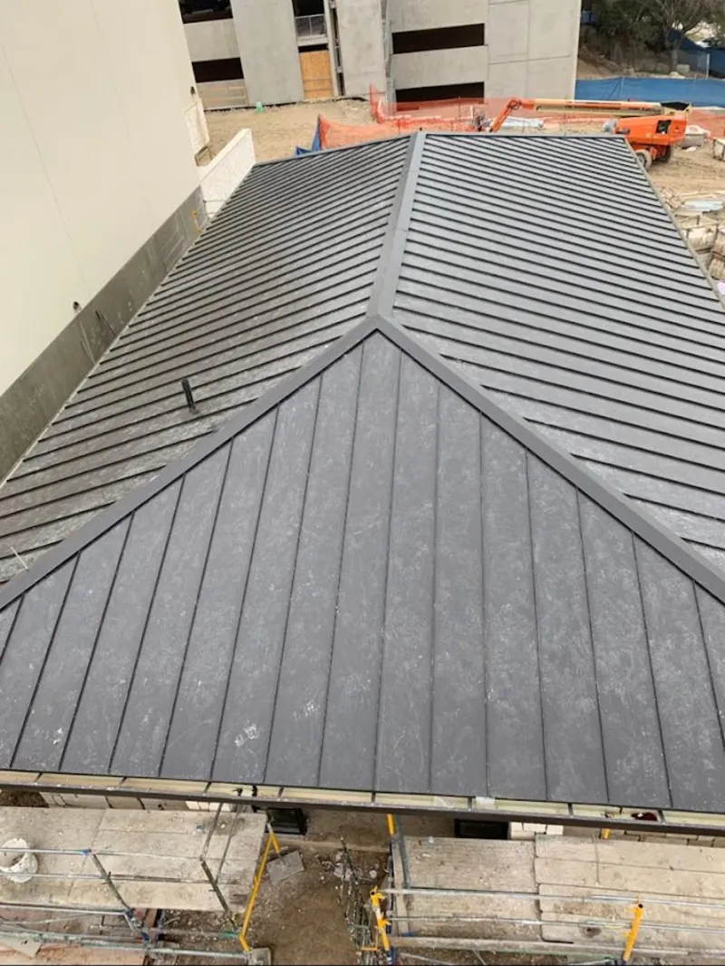 Commercial metal roof construction with crane equipment in Earl